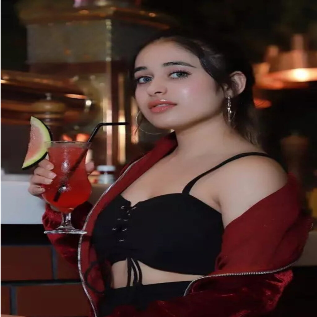 A GIRL 23 YEARS OLD IN RED AND BLACK DRESS STANDING POSITION TAKING JUCE CLASS ON HER HAND